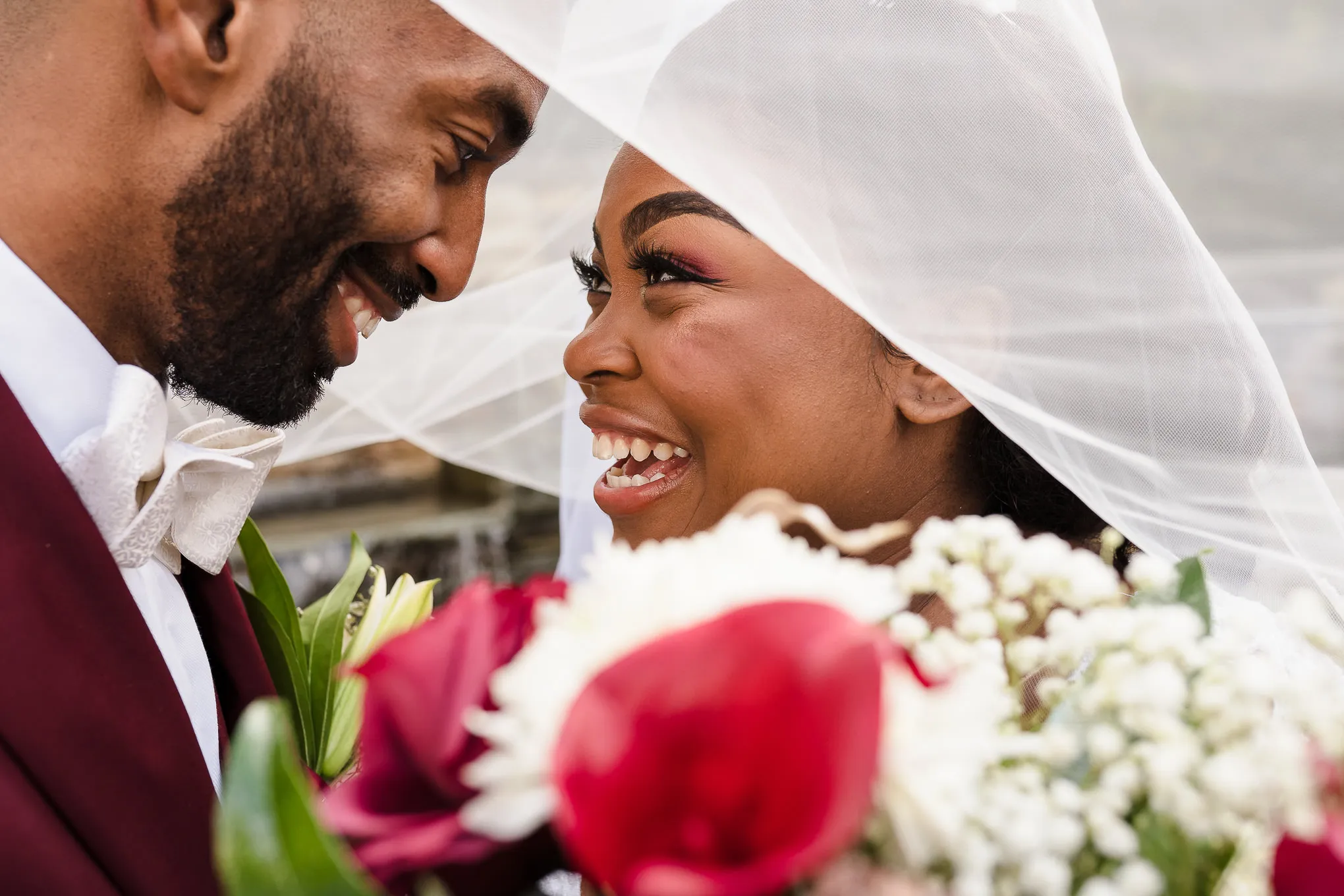 Bride and groom laughing under her veil