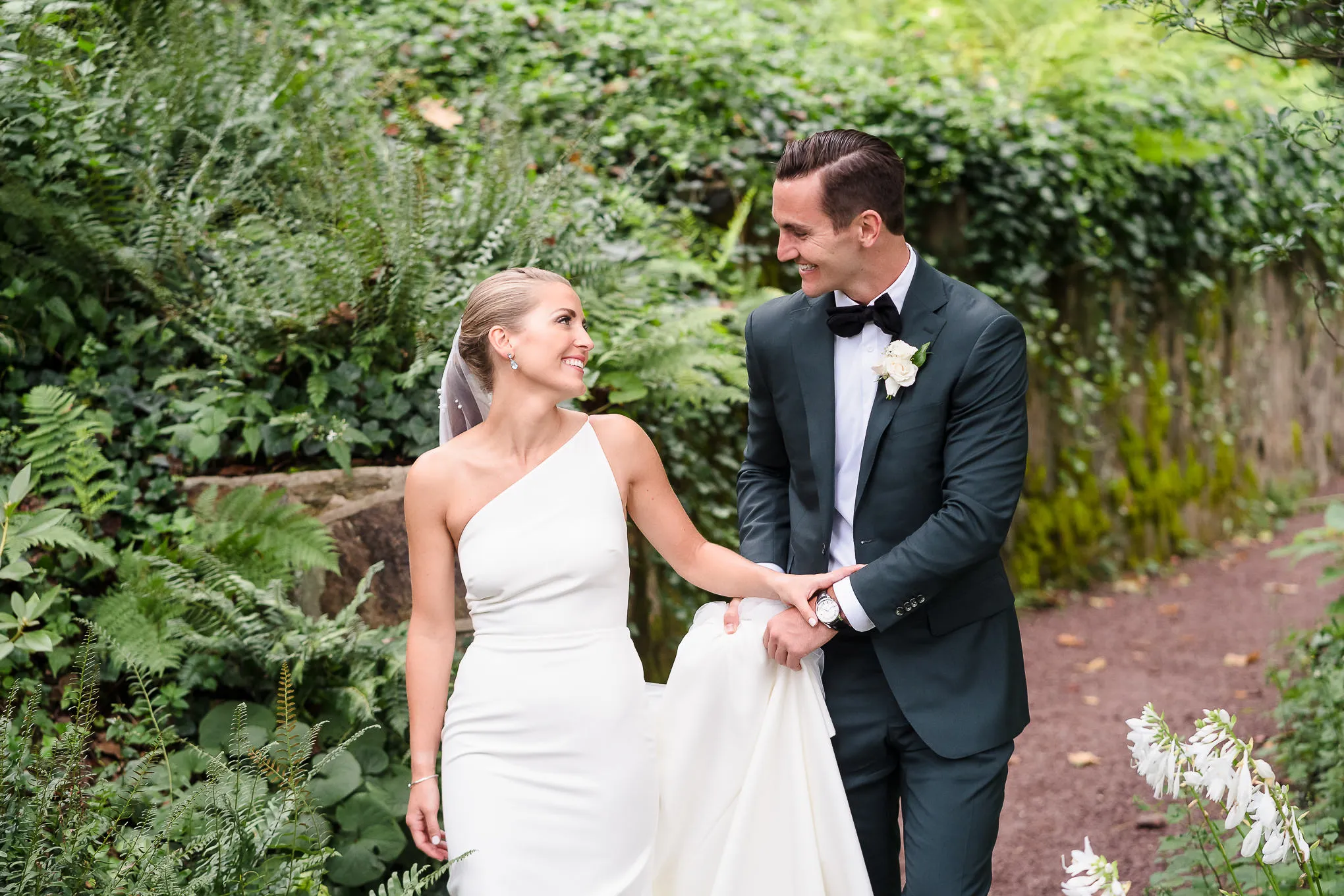 Bride and groom laughing as they walk a garden path