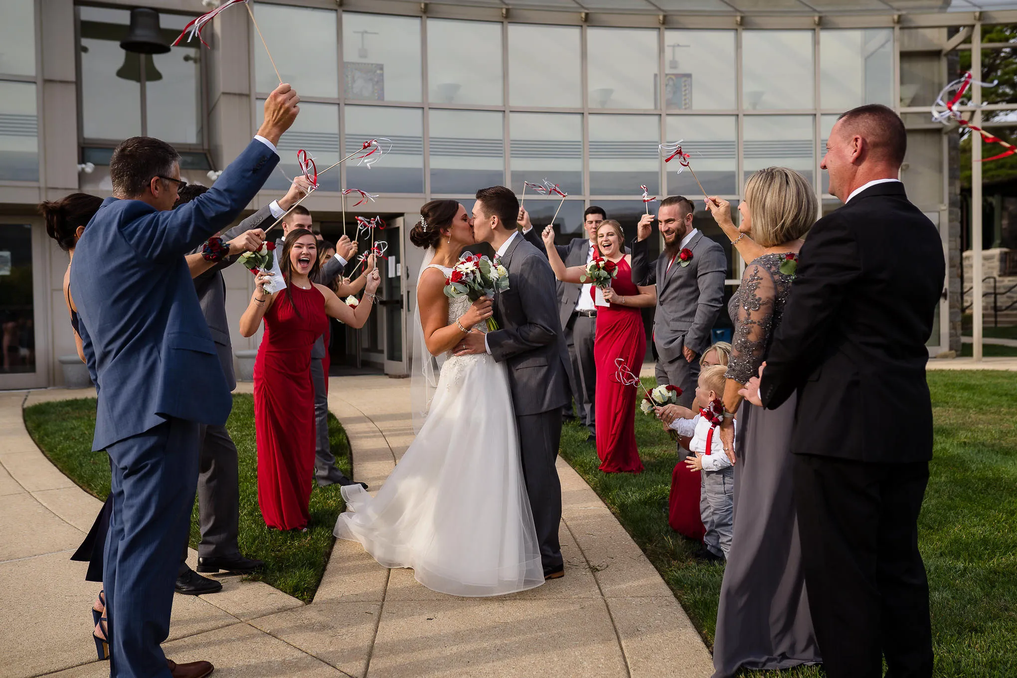 Couple kissing as guests wave ribbon wands at their exit