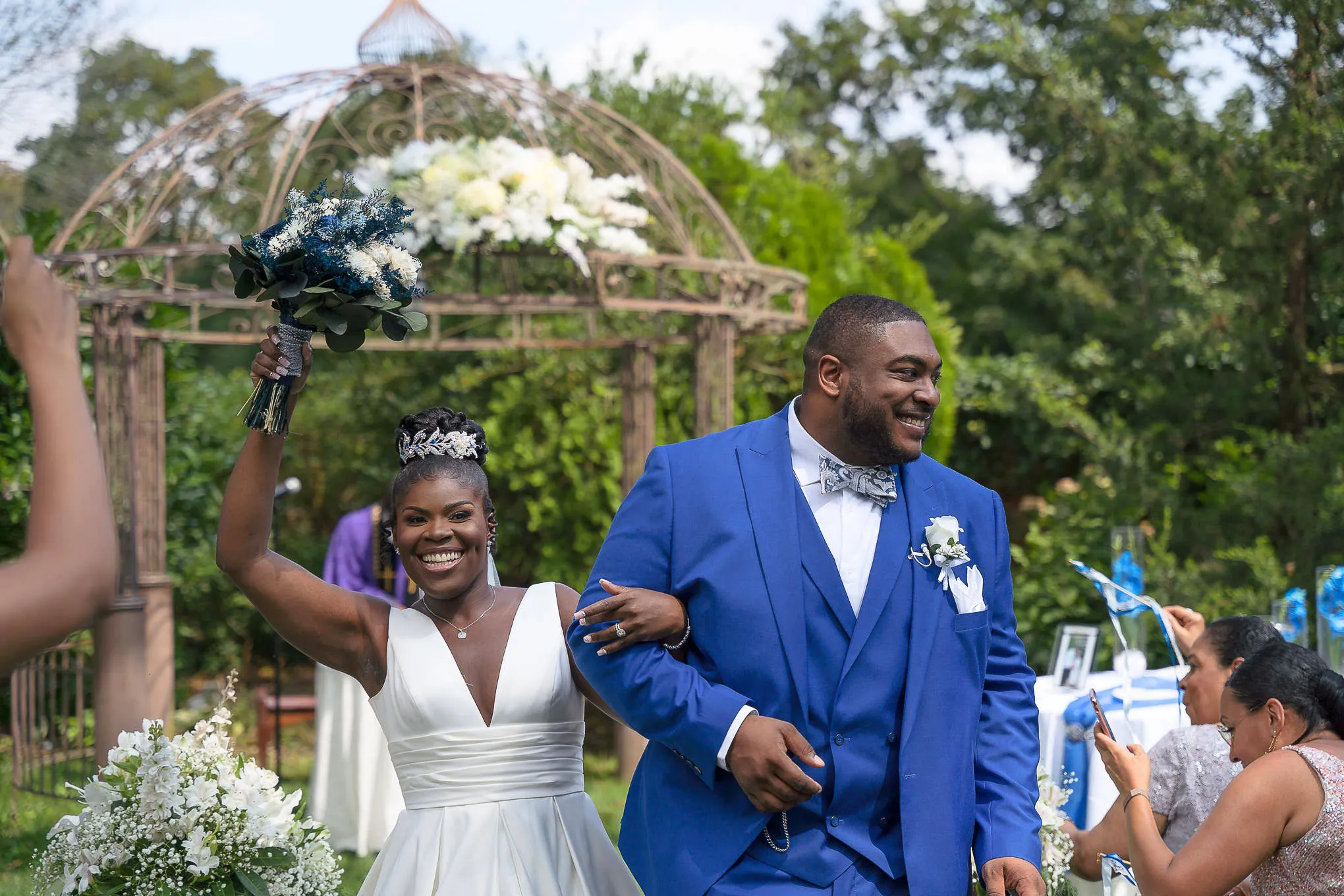 Bride raising her bouquet as she walks back up the aisle with her groom