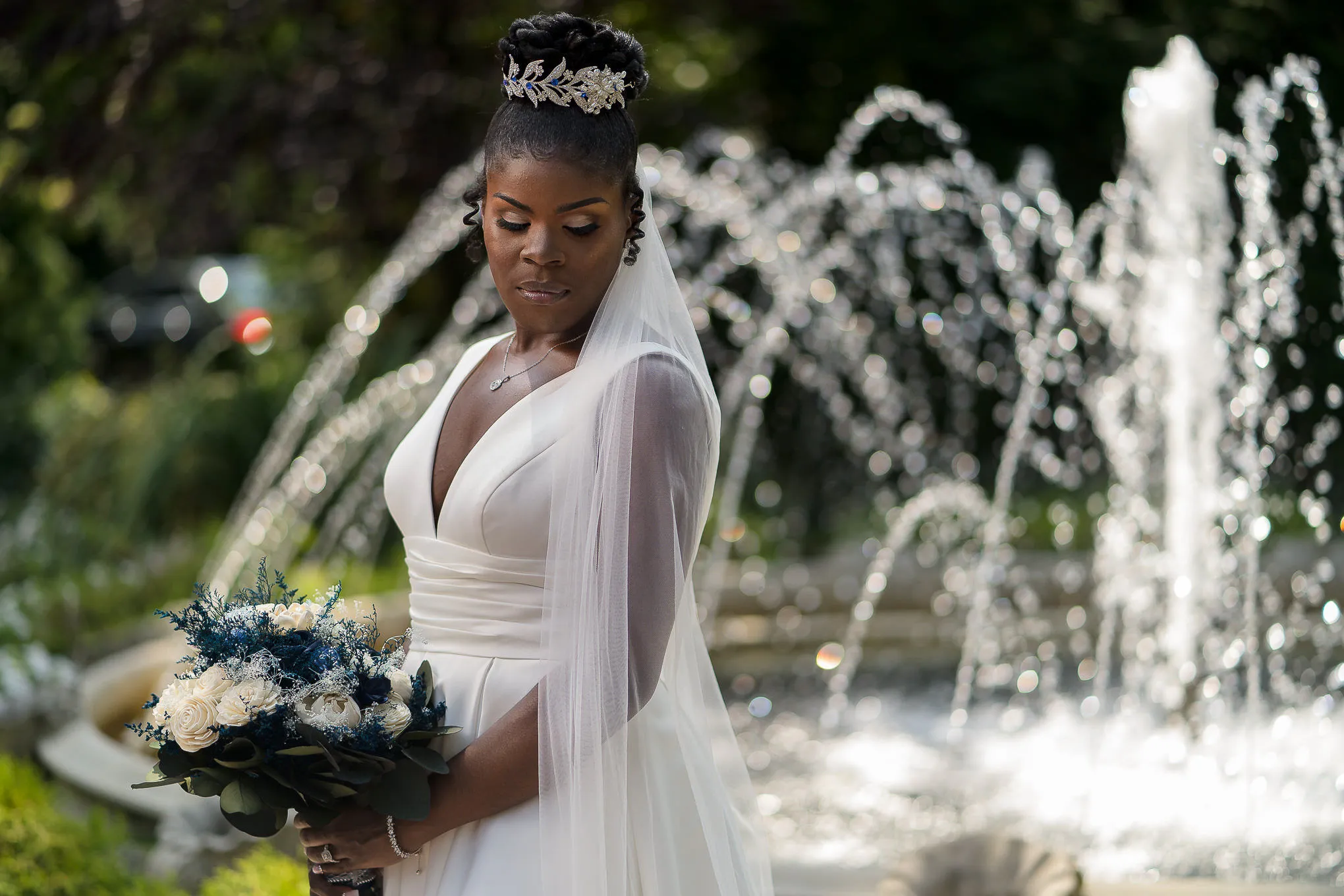 Bride with a navy and white bouquet in front of a garden fountain