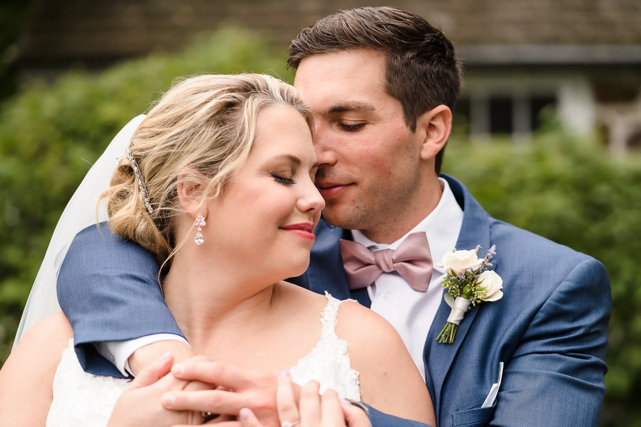 Groom hugging his bride from behind in a garden