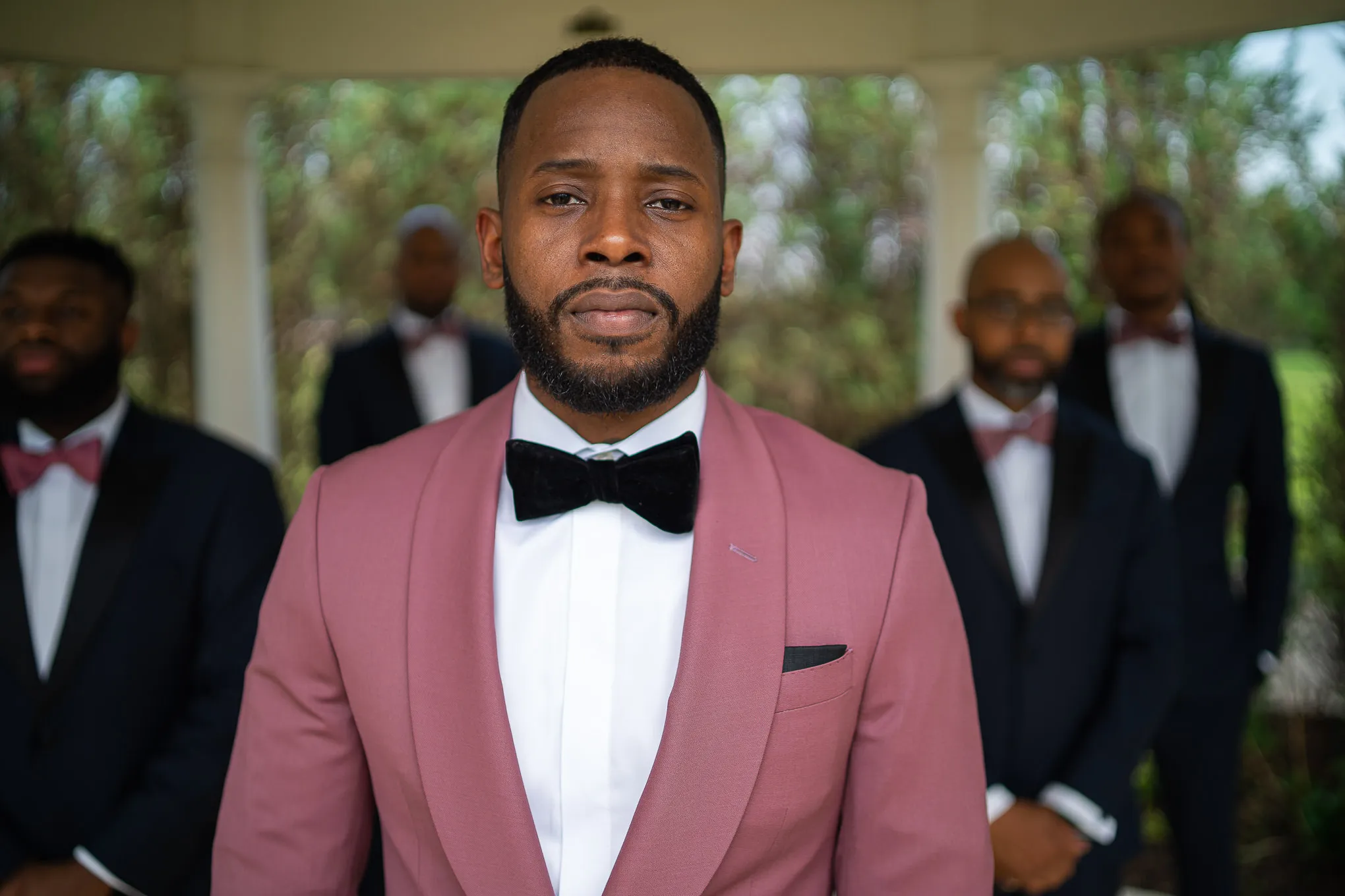 Groom in a pink dinner jacket with his groomsmen behind him