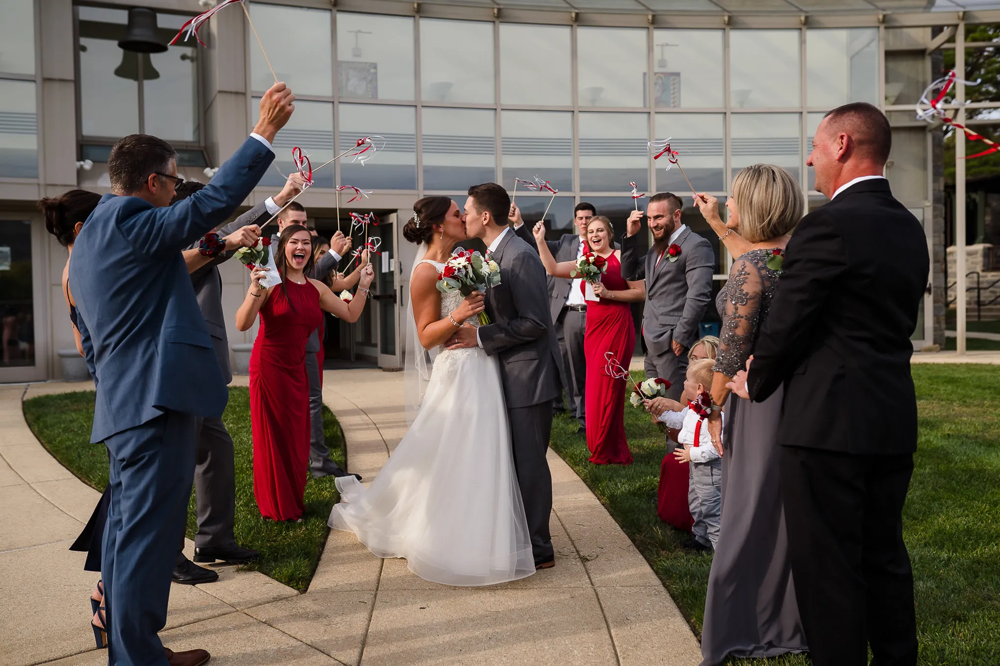 Couple kissing as guests wave ribbon wands at their exit